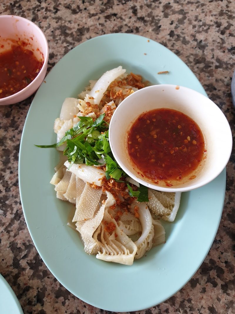 เนื้อสไลซ์บาง ๆ บนจาน โรยผักชี กับถ้วยน้ำจิ้มพริก